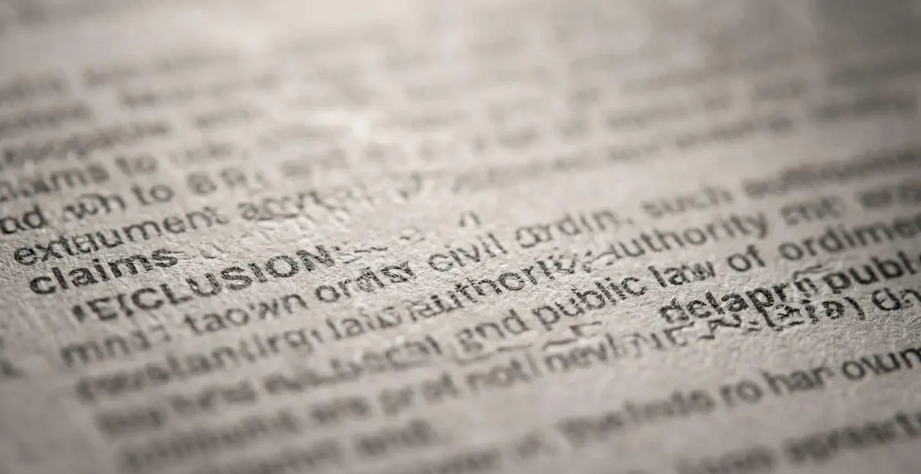 Extreme close-up of insurance policy document showing exclusion clause text with shallow depth of field